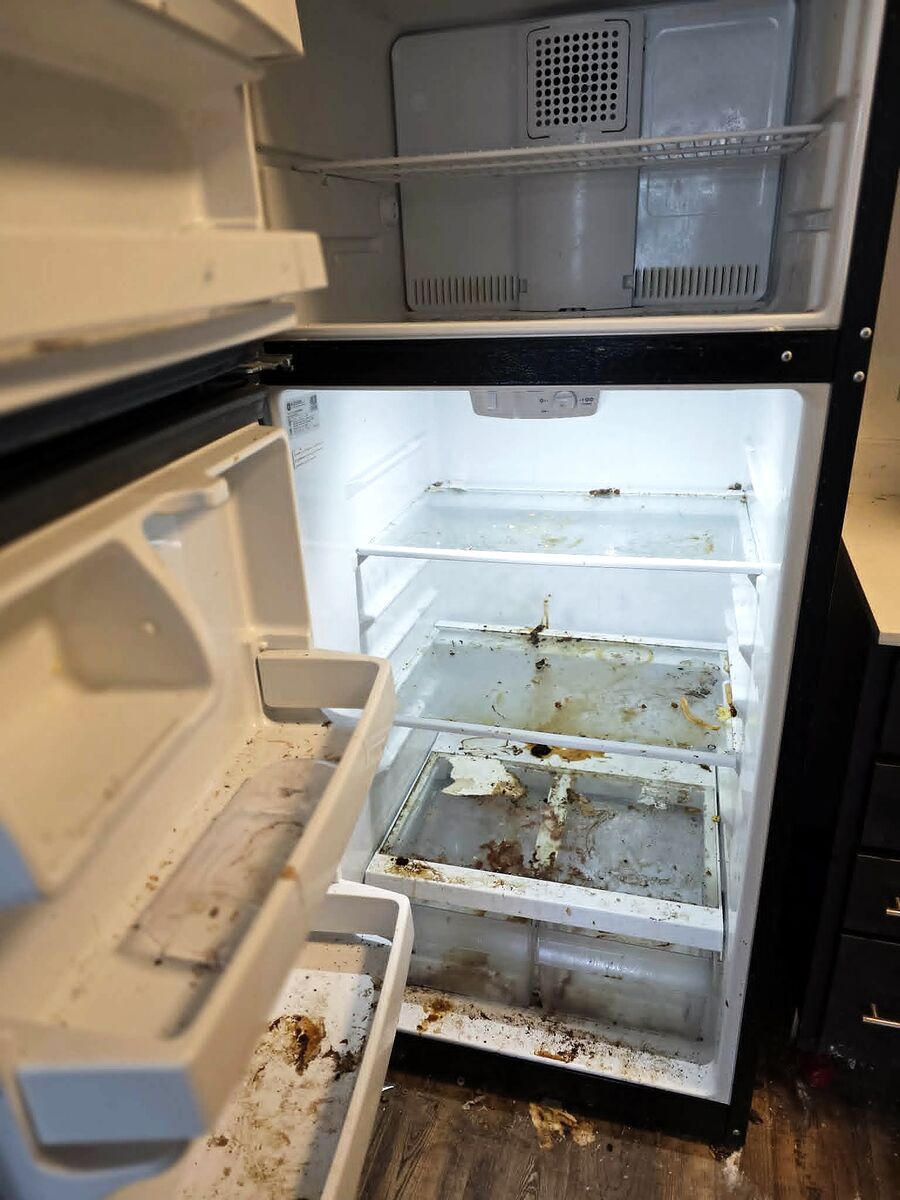 Refrigerator interior before cleaning, with spills and residue